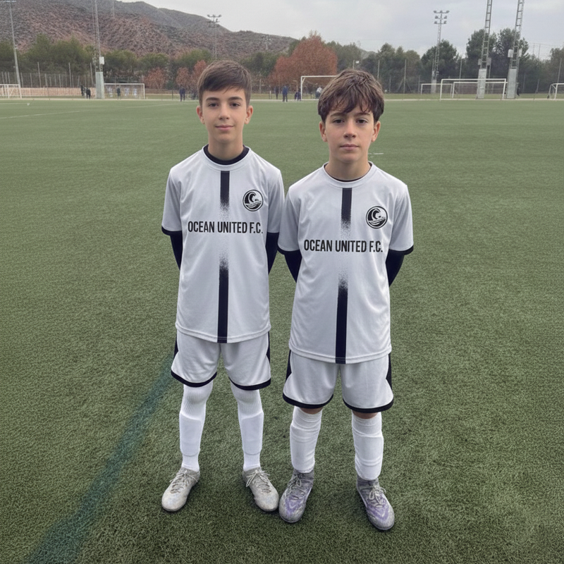 Two young boys in Ocean United F.C. soccer uniforms standing on a grass field.