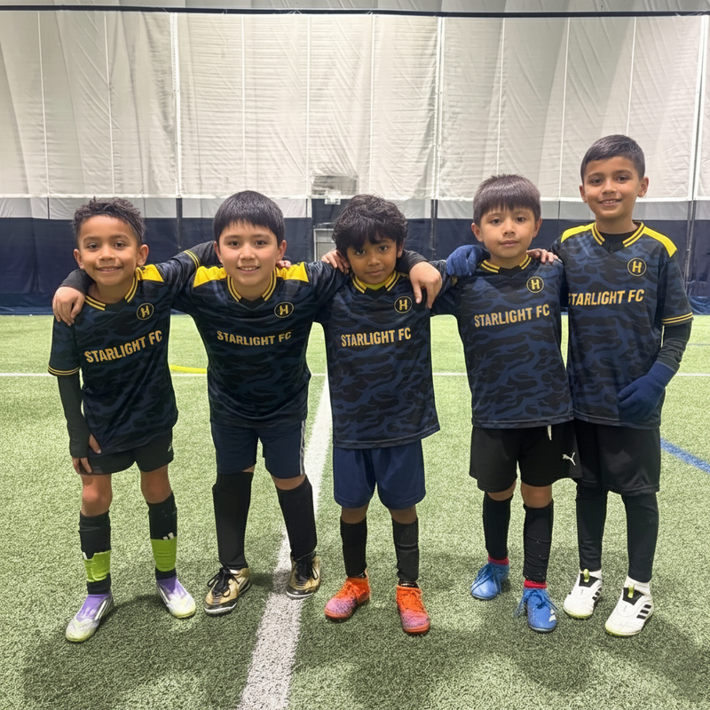 Five children in Starlight FC soccer uniforms posing on a sports field.